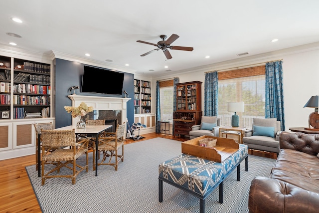 living area with recessed lighting, wood finished floors, visible vents, a high end fireplace, and crown molding