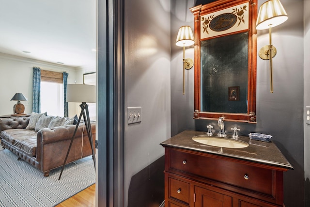 bathroom with wood finished floors, vanity, and crown molding