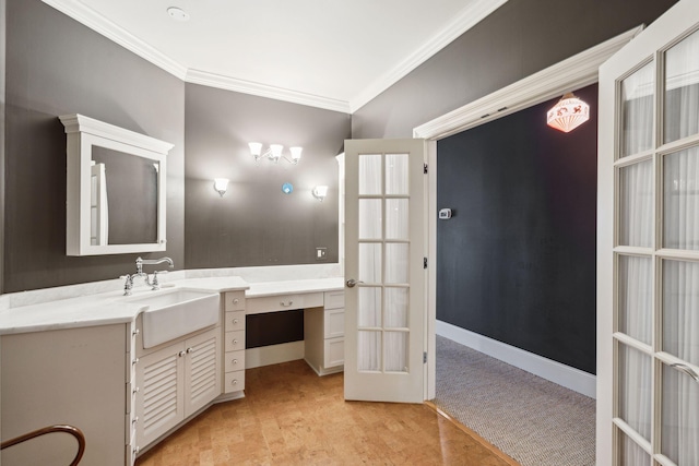 bathroom featuring french doors, ornamental molding, vanity, and baseboards