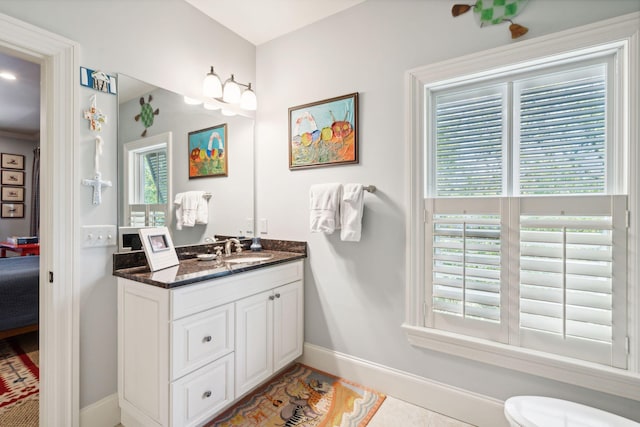 ensuite bathroom with baseboards, toilet, ensuite bath, tile patterned flooring, and vanity