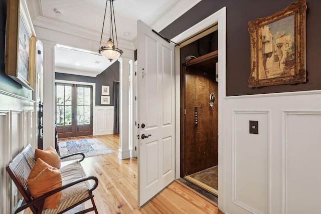 foyer with wainscoting, light wood-type flooring, decorative columns, and crown molding