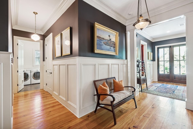 foyer featuring plenty of natural light, ornate columns, independent washer and dryer, and light wood-style floors