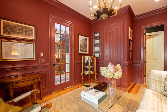 interior space featuring light wood-style flooring, ornamental molding, a decorative wall, and a notable chandelier