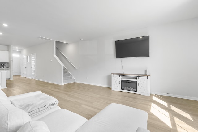 living room with baseboards, stairway, and light wood-style floors