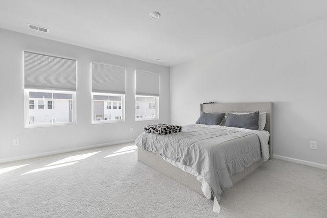 bedroom with light colored carpet, visible vents, and multiple windows