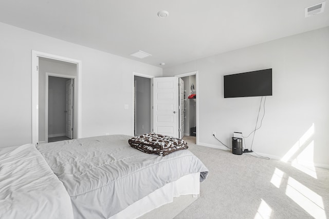 bedroom featuring light carpet, a walk in closet, visible vents, and baseboards