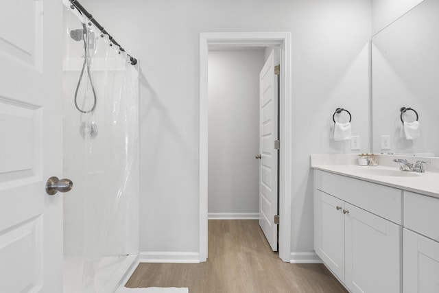 bathroom featuring a stall shower, wood finished floors, vanity, and baseboards