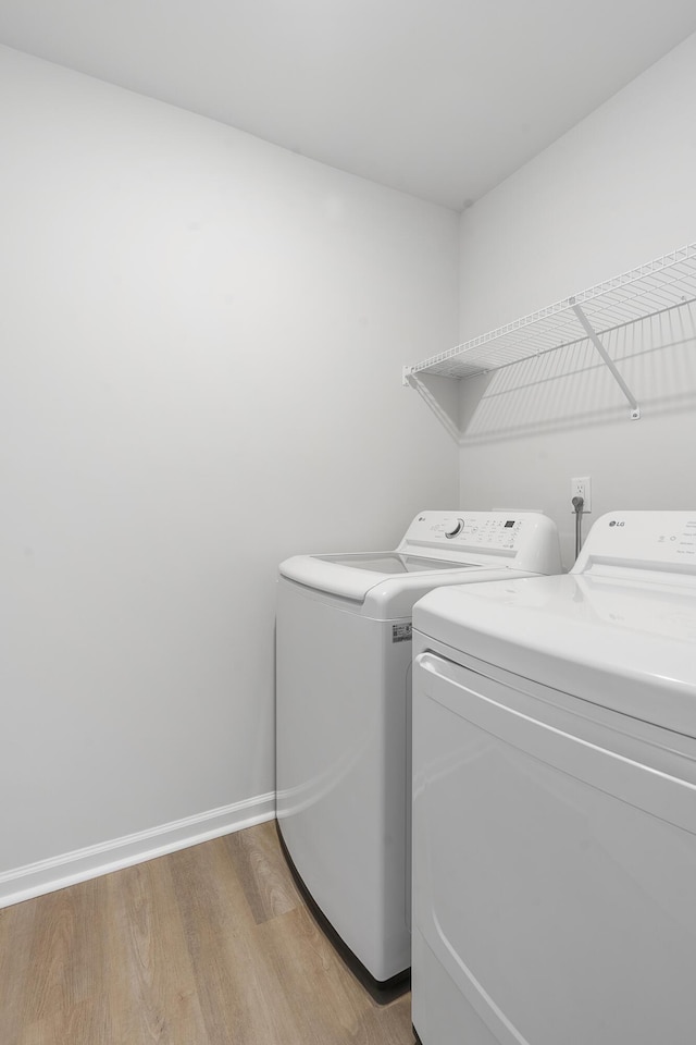 laundry room with laundry area, washing machine and clothes dryer, light wood-style flooring, and baseboards