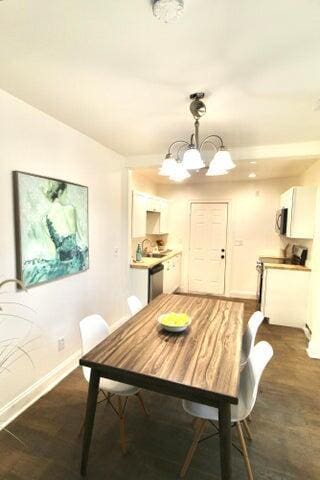 dining space with dark hardwood / wood-style floors and an inviting chandelier