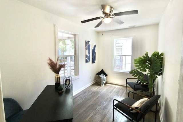 living area with ceiling fan, a healthy amount of sunlight, and dark wood-type flooring