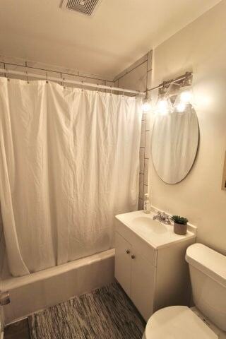 full bathroom featuring shower / bath combo, vanity, and toilet