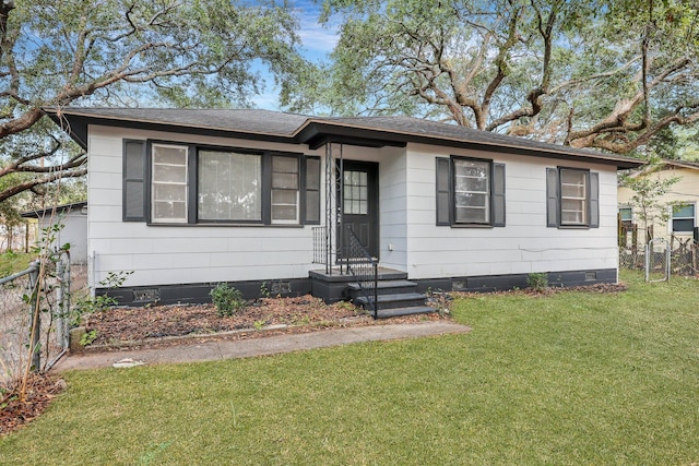 view of front of home with roof with shingles, a front lawn, crawl space, and fence