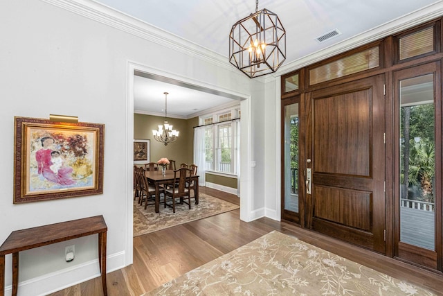 foyer entrance featuring baseboards, visible vents, dark wood-style flooring, ornamental molding, and a chandelier