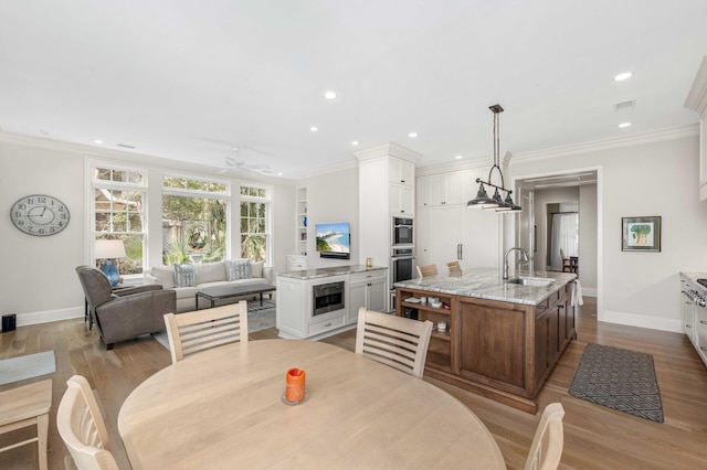 dining area with visible vents, wood finished floors, baseboards, and ornamental molding