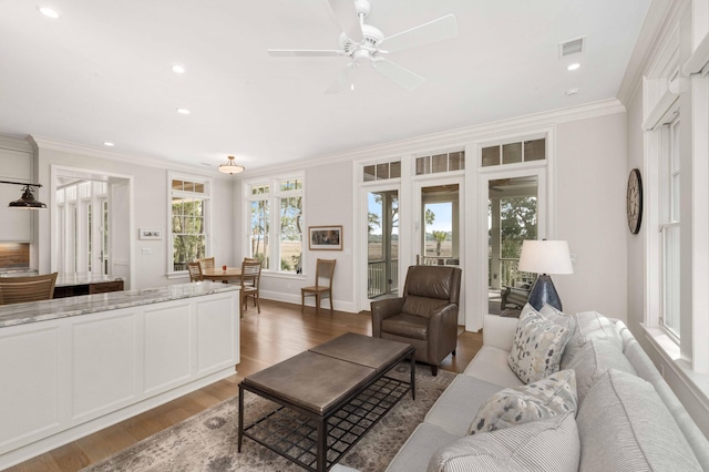 living area featuring visible vents, wood finished floors, a ceiling fan, and ornamental molding