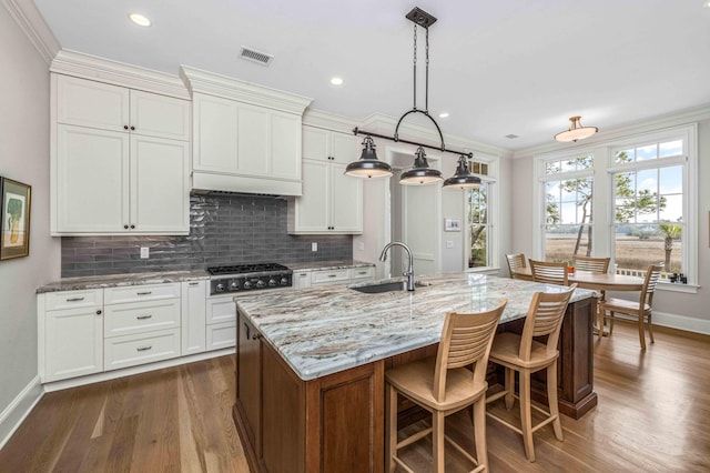 kitchen featuring tasteful backsplash, visible vents, light stone countertops, and a sink