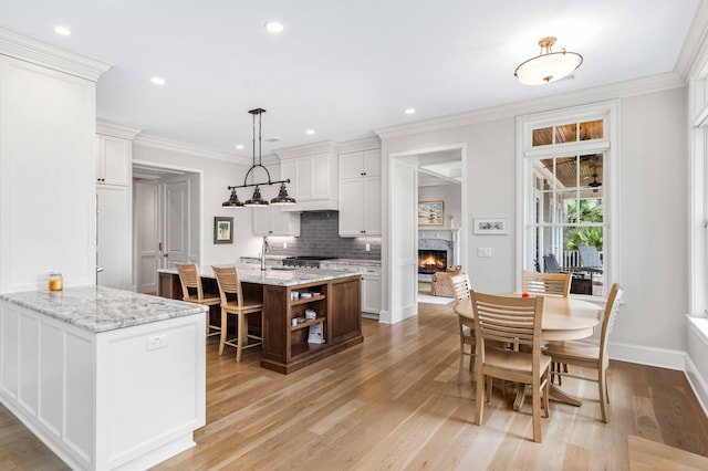 kitchen featuring decorative backsplash, open shelves, light wood-style floors, and a warm lit fireplace