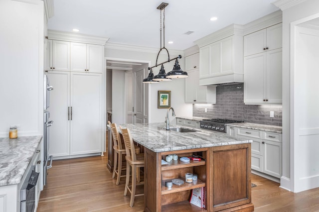 kitchen with open shelves, a sink, decorative backsplash, white cabinets, and light wood-style floors