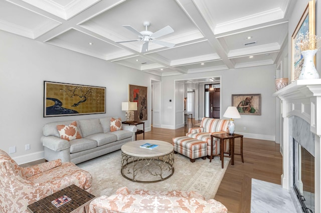 living area featuring baseboards, coffered ceiling, beam ceiling, a high end fireplace, and light wood-type flooring