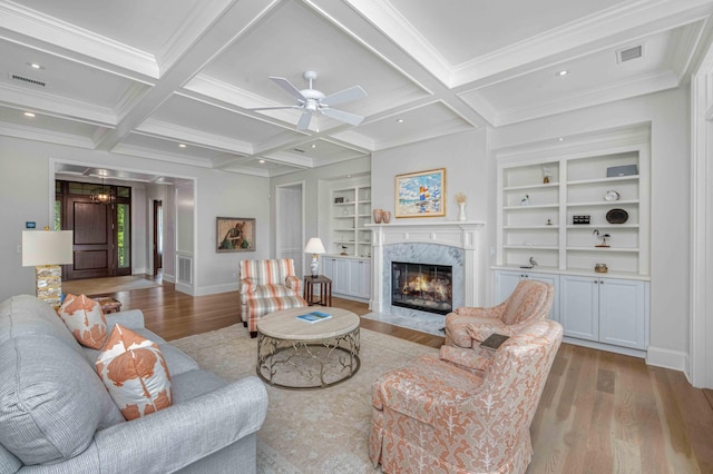 living area with a premium fireplace, visible vents, and wood finished floors