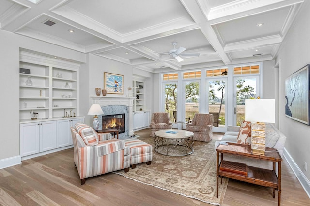 interior space featuring baseboards, beamed ceiling, a fireplace, wood finished floors, and coffered ceiling