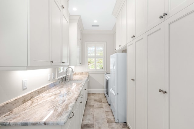 laundry area featuring visible vents, ornamental molding, cabinet space, independent washer and dryer, and a sink