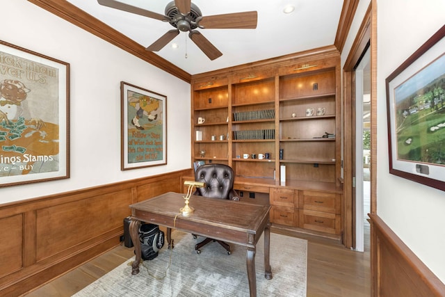 office space with a wainscoted wall, crown molding, ceiling fan, and wood finished floors