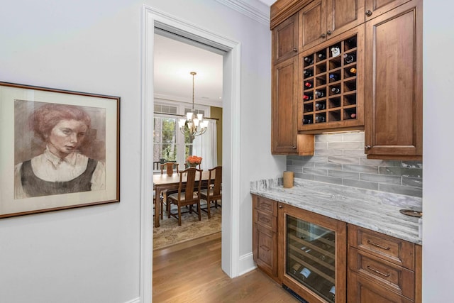 bar featuring decorative backsplash, wine cooler, light wood-type flooring, and ornamental molding