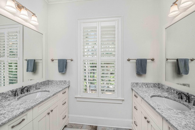 full bath with a sink, baseboards, and two vanities