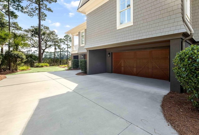 view of side of home featuring concrete driveway, an attached garage, and stucco siding