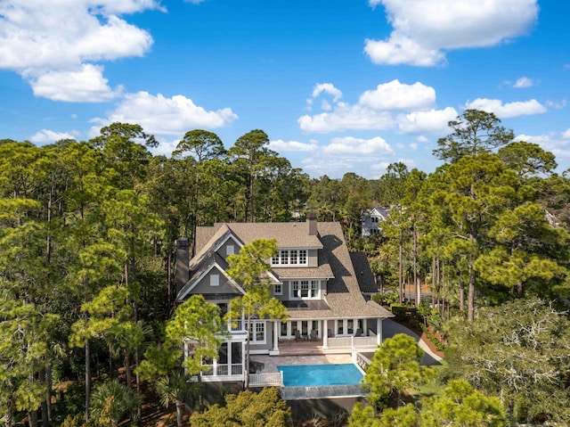 rear view of property featuring an outdoor pool and a chimney