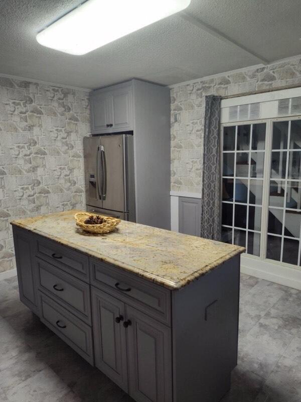225 Baxter Ln, Walterboro, SC 29488 - kitchen featuring stainless steel refrigerator with ice dispenser, a textured ceiling, light stone counters, and gray cabinetry