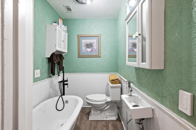 225 Baxter Ln, Walterboro, SC 29488 - full bath featuring wood finished floors, toilet, a freestanding bath, wainscoting, and a textured ceiling