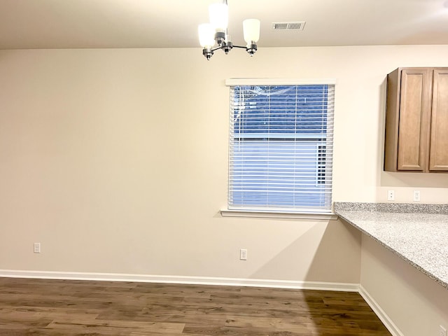 unfurnished dining area with an inviting chandelier and dark hardwood / wood-style flooring