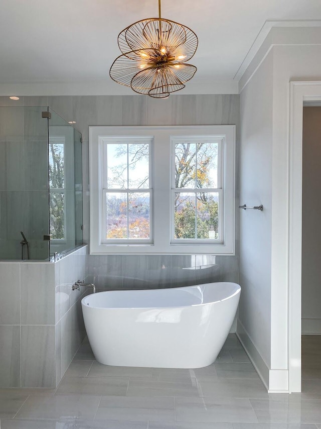 bathroom featuring a wealth of natural light, separate shower and tub, and tile walls