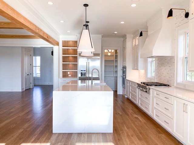 kitchen with appliances with stainless steel finishes, hardwood / wood-style floors, an island with sink, and white cabinets