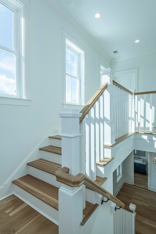 staircase with ornamental molding and wood-type flooring