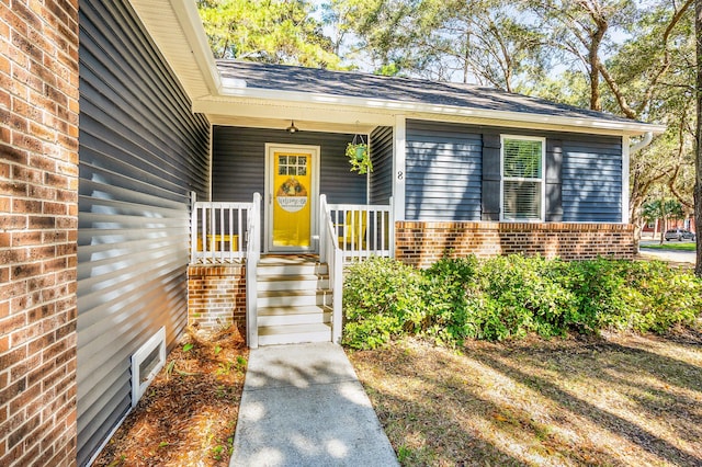 property entrance featuring brick siding and covered porch