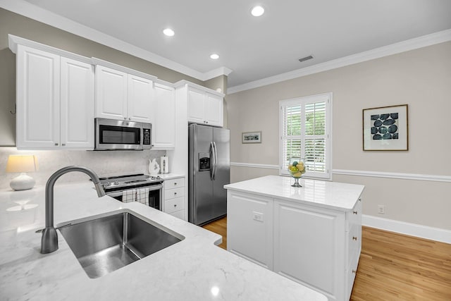 kitchen featuring stainless steel appliances, a sink, ornamental molding, tasteful backsplash, and a kitchen island