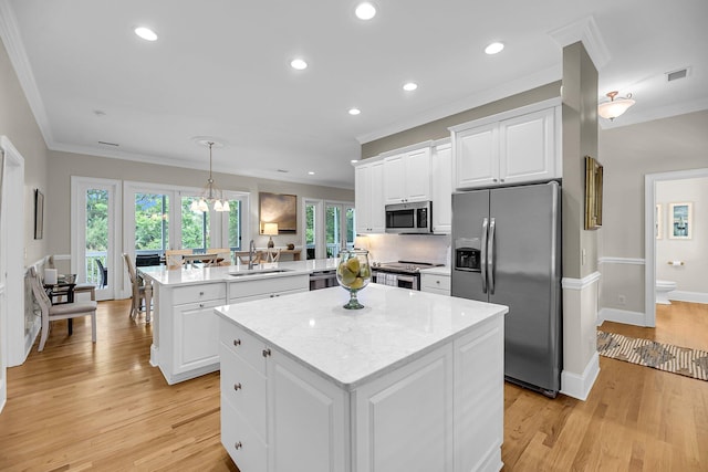 kitchen with appliances with stainless steel finishes, a peninsula, crown molding, a kitchen island, and a sink