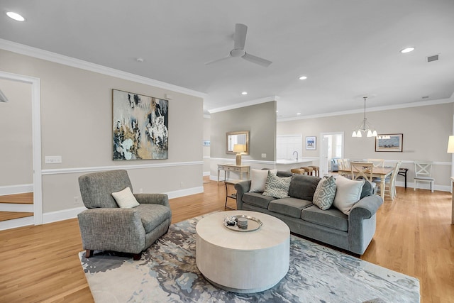 living room with light wood finished floors, a ceiling fan, crown molding, recessed lighting, and baseboards