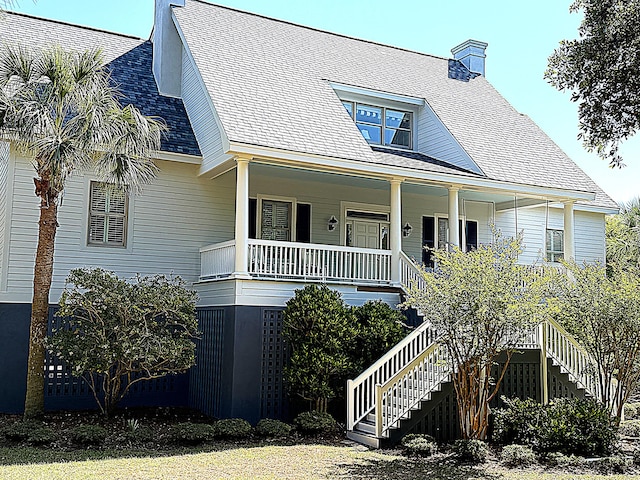 view of front of property with stairs, a porch, a chimney, and a shingled roof