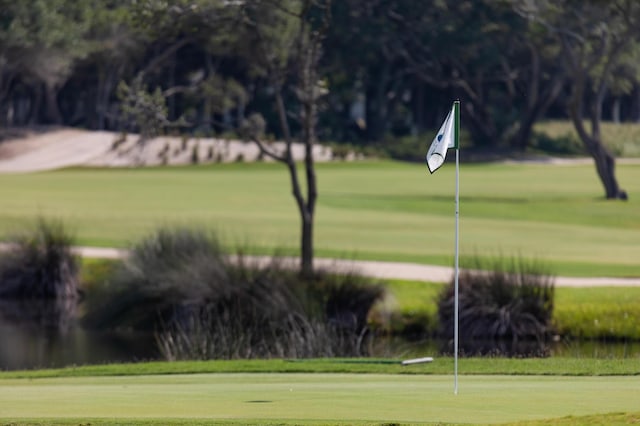 view of community with view of golf course, an area to practice putting, and a yard