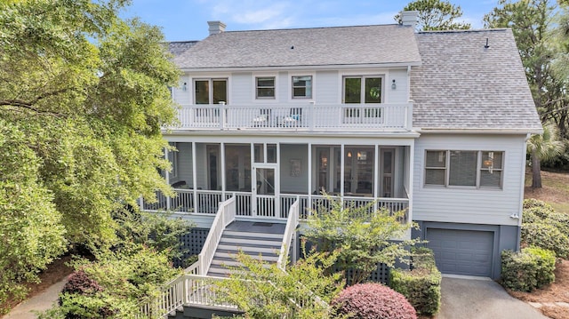 view of front of house featuring stairway, a sunroom, a shingled roof, a garage, and a chimney