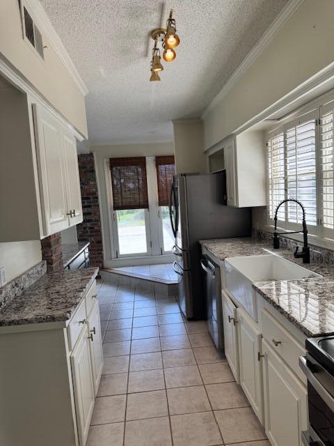 1129 Levi St, Manning, SC 29102 - kitchen featuring a textured ceiling, a sink, light tile patterned floors, dishwasher, and white cabinets