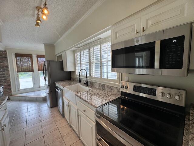 1129 Levi St, Manning, SC 29102 - kitchen featuring stainless steel appliances, a textured ceiling, a sink, light tile patterned floors, and white cabinets