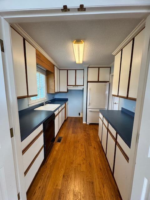 1129 Levi St, Manning, SC 29102 - kitchen featuring freestanding refrigerator, dark countertops, wood finished floors, black dishwasher, and a sink