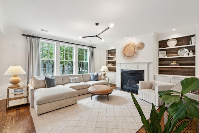 1407 Wando View St, Daniel Island, SC 29492 - living room with crown molding, light wood-type flooring, built in features, a chandelier, and a fireplace with flush hearth