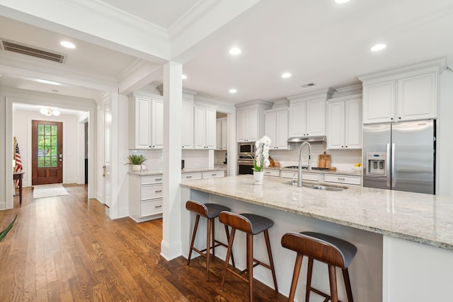 1407 Wando View St, Daniel Island, SC 29492 - kitchen with stainless steel appliances, ornamental molding, under cabinet range hood, white cabinets, and a breakfast bar