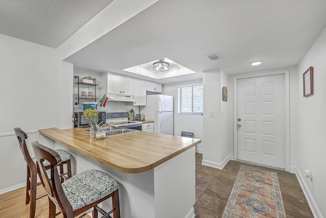 2174 Bees Ferry Rd Unit G, Charleston, SC 29414 - kitchen featuring white appliances, white cabinetry, a breakfast bar area, a peninsula, and under cabinet range hood